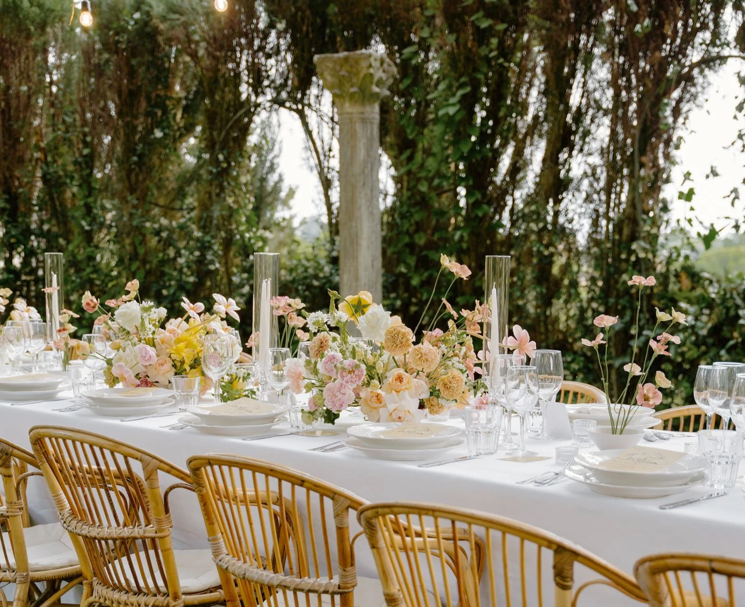 Imperial table under trees laid with peach and yellow centrepieces