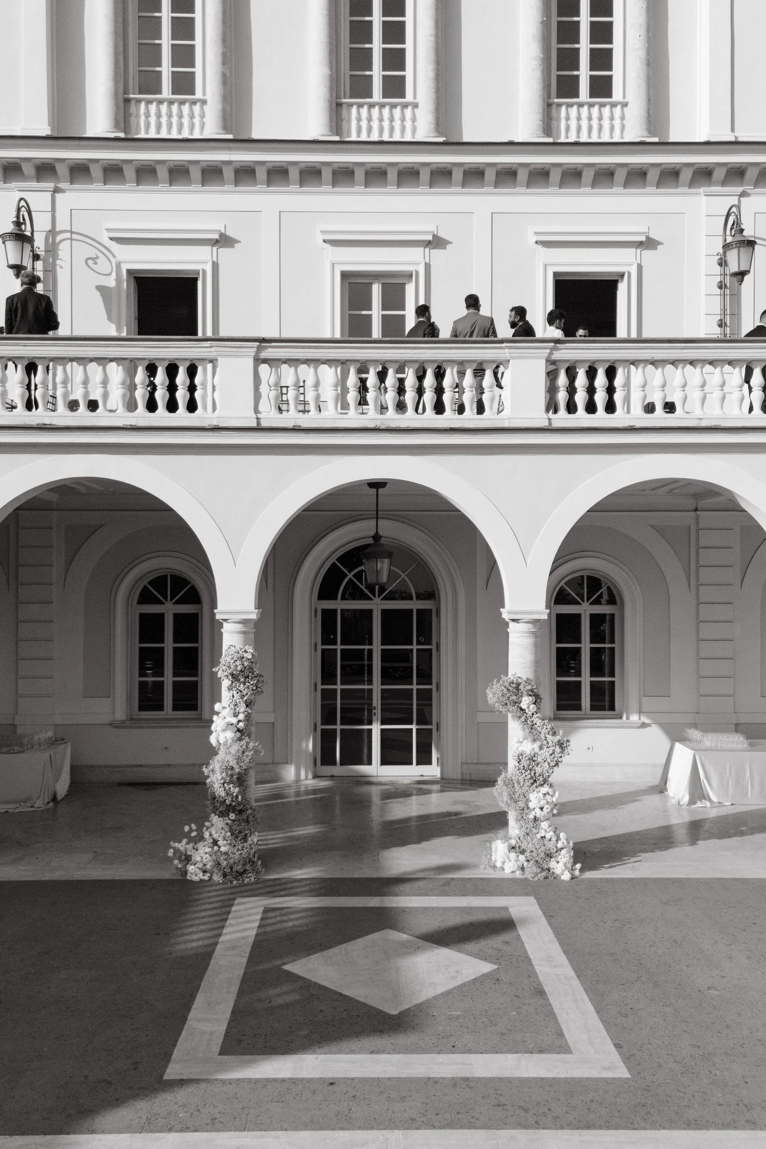 Black and white view of a villa loggia framed by tall white floral columns