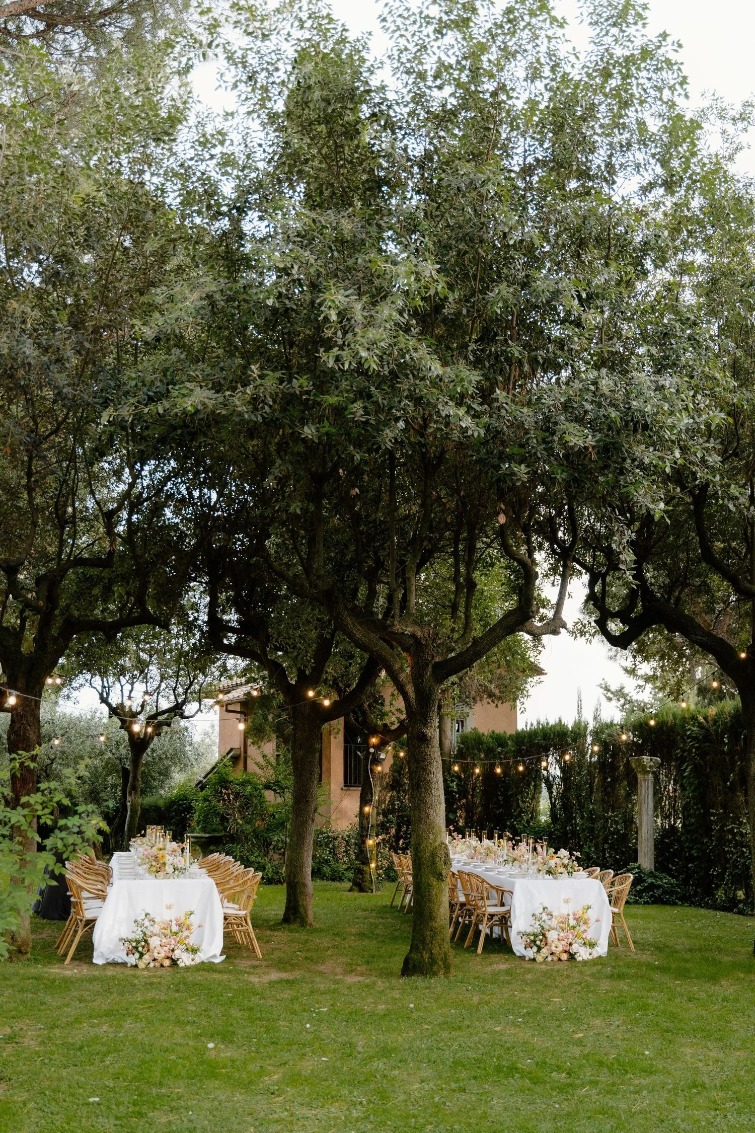 Olive grove dinner set with candles and low floral arrangements at dusk
