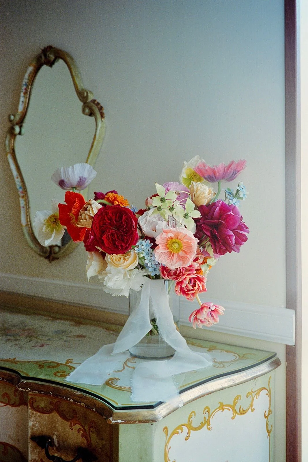 Vivid coral and pink arrangement on a painted antique console