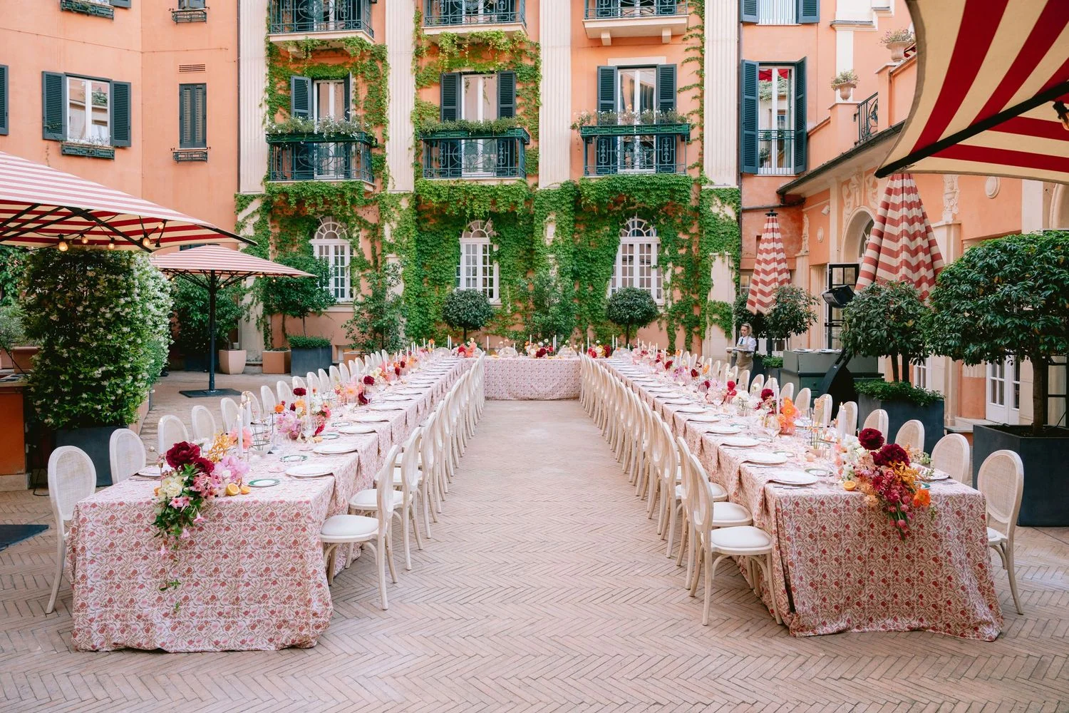 Courtyard reception under striped awnings with long floral tables