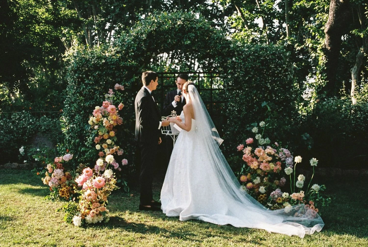 Outdoor wedding ceremony at Villa Aurelia beneath a floral arch.