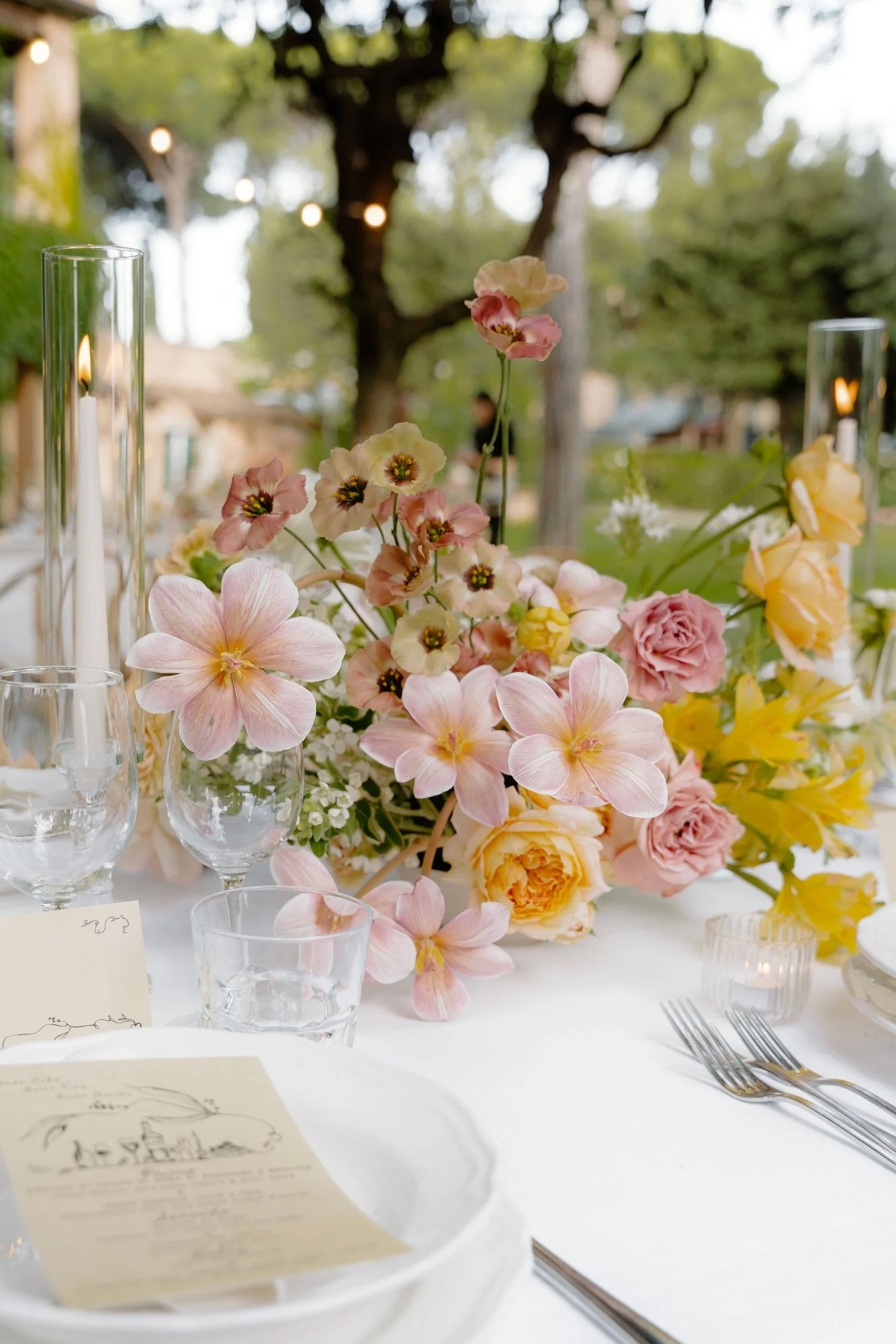 Pastel centrepiece of dahlias and roses running along a candlelit table