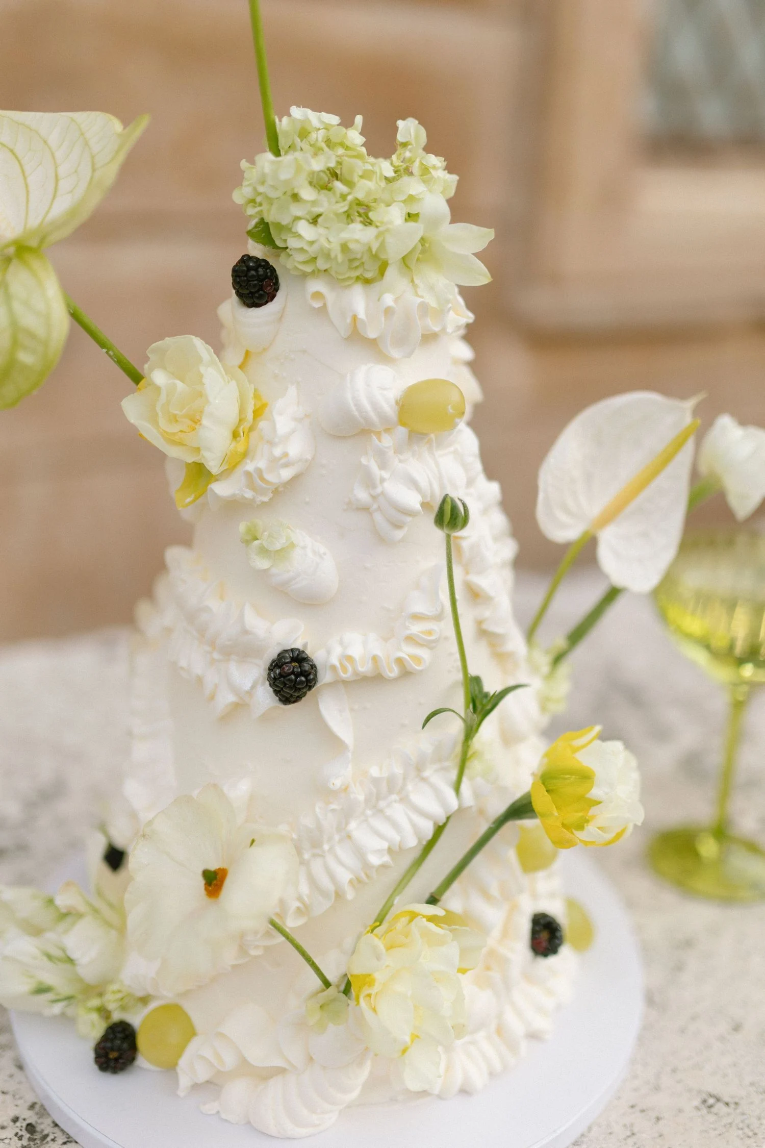 Wedding cake dressed with white anthurium, ranunculus and blackberries